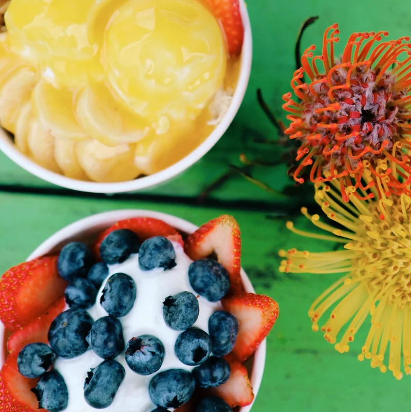 Açaí bowls with liliko'i drizzle beside a protea flower